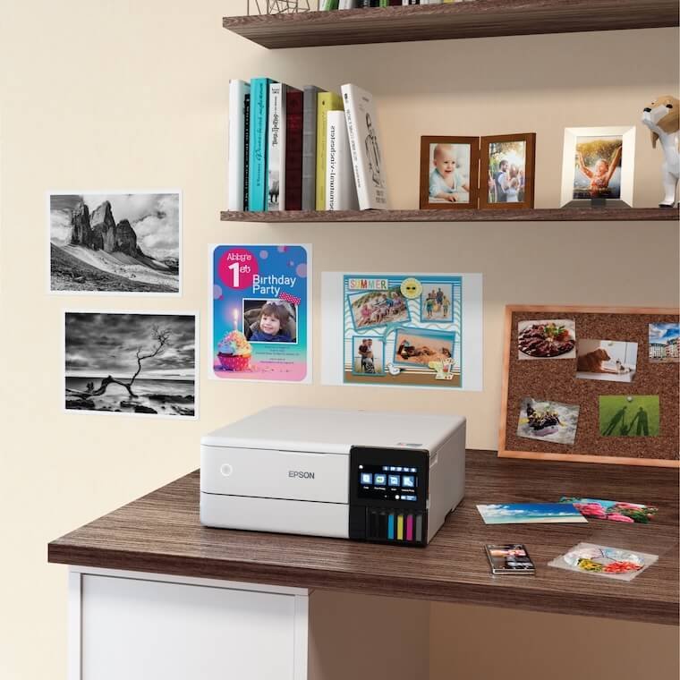 Epson EcoTank printer sitting in a room desk near prints