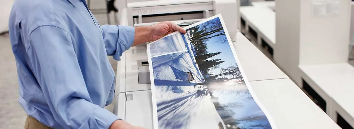 Woman printing out a large photo on a production printer