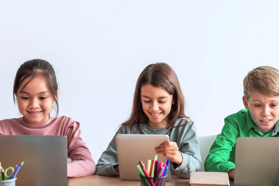 Elementary students using laptops together in a classroom