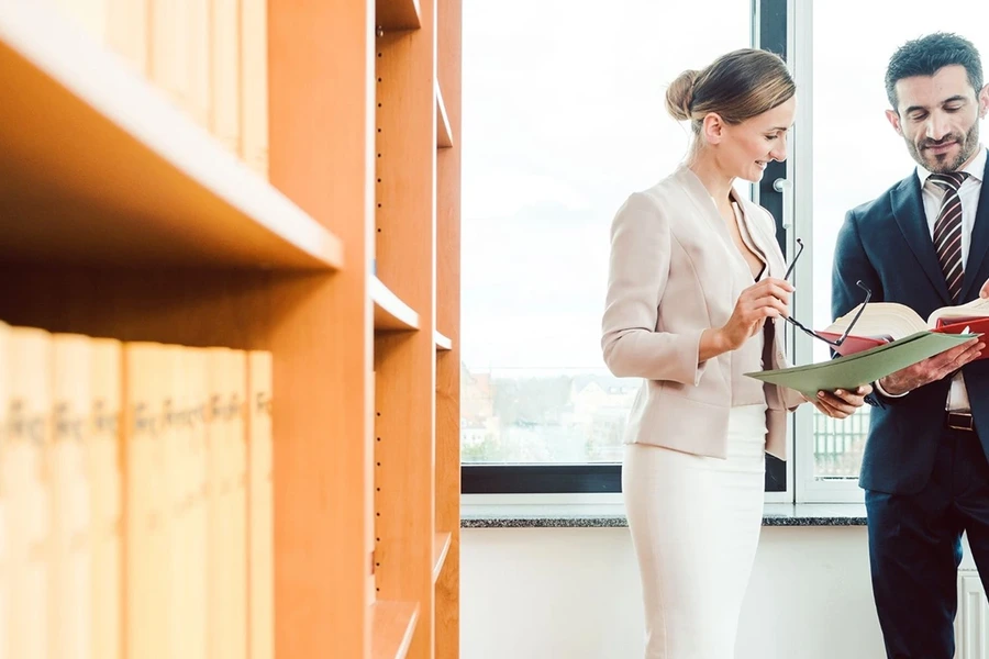 Legal professionals collaborating in front of law bookshelves