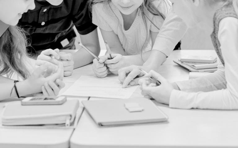Kids in a classroom with paper assignments on table