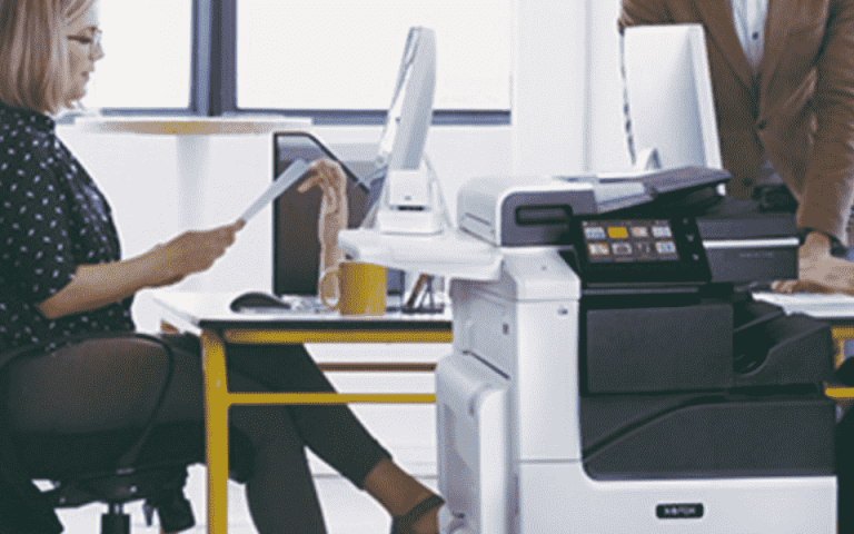 Five people around a desk with the Xerox VersaLink C7130 in front of it