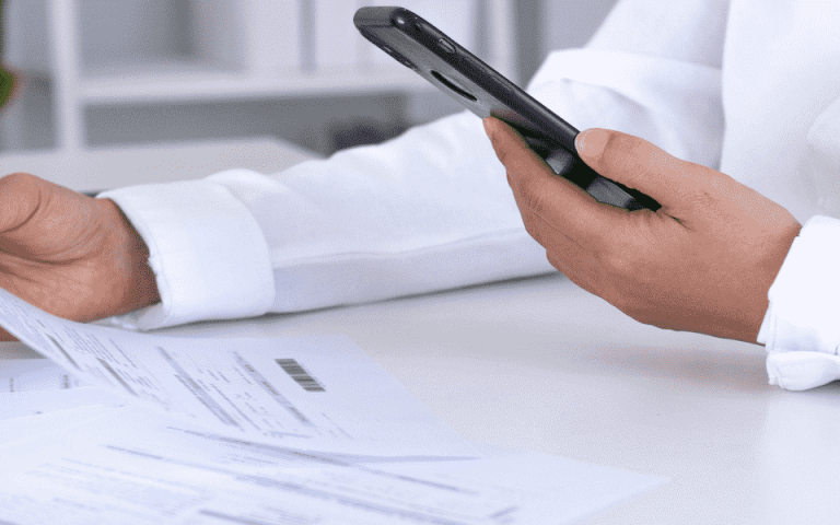 A person scanning a document at a desk with an iPhone