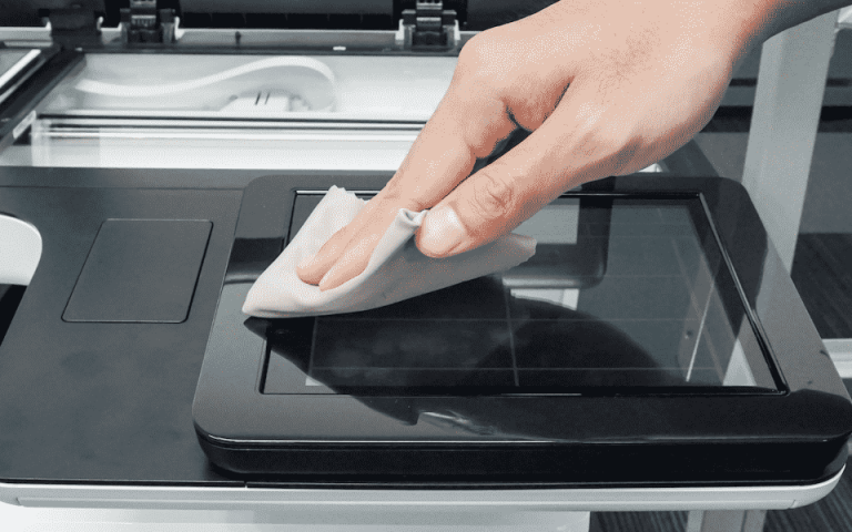 Person using a cloth to clean the glass on a printer