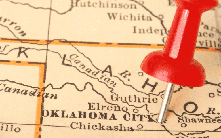 A close up view of a map of Oklahoma with a red thumb tack pinned on Oklahoma City
