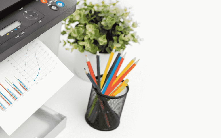 A printer next to a plant and a pencil holder