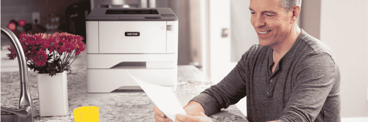 Person smiling while looking at a piece of paper next to the Xerox B310
