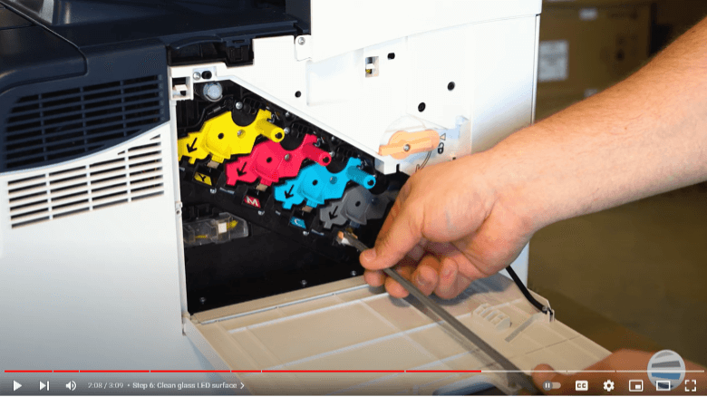 Screenshot of a printer technician cleaning the glass lenses