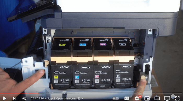 Printer technician points to 2 orange buttons on side cover of Xerox C410/C415